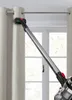 A vacuum cleaner is being used to clean curtains in front of a window. Anteprima dell’immagine prodotto