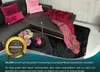 A sectional sofa with decorative pillows and a blanket, a coffee table with flowers and a candle, and a fluffy rug. Produktbild-Vorschau