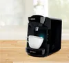 A black Bosch Tassimo coffee machine with a white cup is placed on a wooden table. Náhľad obrázku produktu