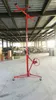 A red drywall lift is standing in a warehouse or workshop with stacks of boxes in the background. Anteprima dell’immagine prodotto
