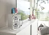 A white controller stand with game controllers and a Nintendo Switch on top, placed on a white cabinet next to a television. Produktbild-Vorschau