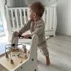 A baby is using a wooden walker with various activity toys attached. Produktbild-Vorschau