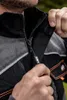 A close-up of a person's hands zipping up a black and gray work jacket. Produktbild-Vorschau