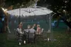 People dining outdoors under a large umbrella with a mosquito net enclosure at night. Anteprima dell’immagine prodotto
