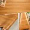 A collage of images showing a wood-grain patterned adhesive vinyl roll. Anteprima dell’immagine prodotto