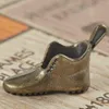 A close-up of a miniature bronze shoe, possibly a game piece, resting on a surface with printed text. Produktbild-Vorschau