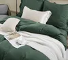 A neatly made bed with green bedding, white blanket, and decorative pillows. Podgląd zdjęcia produktu