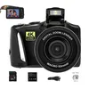 A black digital camera with accessories laid out below it. Produktbild-Vorschau