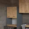A laundry room cabinet with a washing machine underneath. The cabinet has wooden doors and gray sides. Produktbild-Vorschau