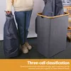 A person is holding a laundry bag next to a multi-compartment laundry hamper. Produktbild-Vorschau