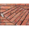 A roll of wallpaper with a brick pattern is shown, partially unrolled over a background that also features the brick pattern. Produktbild-Vorschau