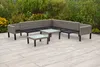 An outdoor sectional sofa and two coffee tables are arranged on a patio with a garden in the background. Produktbild-Vorschau
