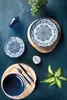 A table setting with plates, cutlery, a wine glass, and a plant. Anteprima dell’immagine prodotto