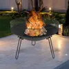 A fire pit with a fire burning in it, set up on a patio at night with garden lights in the background. Náhľad obrázku produktu