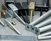 A collection of metal post anchors and rebar on a gray surface. Náhľad obrázku produktu