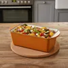 A roasted vegetable dish in an orange casserole dish on a wooden table, with a kitchen in the background. Produktbild-Vorschau