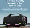 A black portable speaker with colorful LED lights is placed on a rocky surface with a blurred background of water and hills. Produktbild-Vorschau