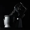 A black hand mixer with two bowls is shown against a black background. Produktbild-Vorschau