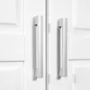 A close-up view of two silver handles on a white cabinet or wardrobe. Produktbild-Vorschau