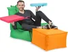 A man is sitting on a green beanbag chair, holding a pink cushion in one hand and a turquoise cushion in the other. An orange ottoman is in front of him. Produktbild-Vorschau