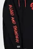 Close-up of the sleeve of a black hoodie with red text and a logo. Podgląd zdjęcia produktu