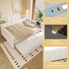A white daybed with a pull-out trundle bed, styled with bedding and pillows, in a room setting. Inset images highlight product features. Náhled obrázku produktu