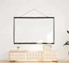 A projection screen is hanging on a white wall above a wooden cabinet. Náhled obrázku produktu
