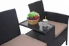 A close-up view of a black poly-rattan bench with a small table attached, featuring a bowl of fruit and a drink. Produktbild-Vorschau
