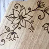 A close-up of a wooden surface with intricate wood-burned floral designs. Podgląd zdjęcia produktu