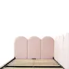 A close-up view of the headboard and slatted base of a pink upholstered bed frame against a white background. Podgląd zdjęcia produktu