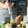 A person is using an immersion blender to make pesto in a glass container, with ingredients like basil, olive oil, and parmesan cheese visible. Produktbild-Vorschau