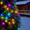 A close-up of a Christmas tree decorated with colorful lights, with a snowy house in the background. Produktbild-Vorschau