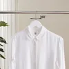 A white shirt hanging on a wooden hanger, with a graphic indicating 360-degree rotation. Produktbild-Vorschau