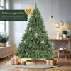 A decorated artificial Christmas tree in a cozy room setting with gifts and decorative items. Produktbild-Vorschau