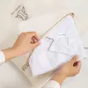 Hands folding a white shirt into a mesh laundry bag. Produktbild-Vorschau