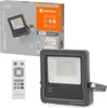 A product shot of a LED floodlight and its remote control, with the product packaging in the background. Produktbild-Vorschau