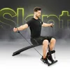 A man is exercising on a slant bench with resistance bands attached to his ankles and hands. The background has large, glowing yellow letters spelling out 'Slant'. Anteprima dell’immagine prodotto