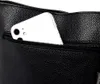 A close-up view of a black handbag with a smartphone partially inserted into an exterior zippered pocket. Náhľad obrázku produktu