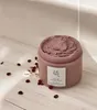 A jar of red bean refreshing pore mask is placed on a light-colored wooden surface, with scattered red beans around it. Produktbild-Vorschau