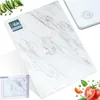 A marble-patterned glass cutting board is shown with some vegetables and tomatoes around it, and a smaller image of the product in its packaging in the bottom left corner. Náhľad obrázku produktu
