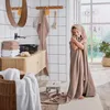 A young girl wrapped in a hooded towel in a bathroom. Produktbild-Vorschau