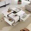 A modern white coffee table with black accents and multiple drawers, placed on a carpeted floor in a living room setting. Voir les images du produit