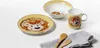 A children's dinnerware set with a lion theme, including a plate, bowl, and mug, along with wooden cutlery and a napkin, arranged on a white surface. Anteprima dell’immagine prodotto