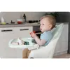 A baby sitting in a high chair in a kitchen setting, playing with toys. Produktbild-Vorschau