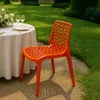 An orange chair is placed next to a table set for a meal in an outdoor garden setting. Produktbild-Vorschau