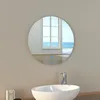 A round LED bathroom mirror is mounted on a wall above a white sink, reflecting a window overlooking the ocean. Produktbild-Vorschau
