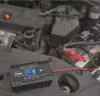A car battery charger is connected to a car battery in an engine bay. Náhled obrázku produktu
