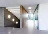 A modern interior hallway with a concrete staircase and a glass-walled office space. Produktbild-Vorschau