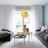 A modern living room with a large gold pendant light hanging over a coffee table. Produktbild-Vorschau