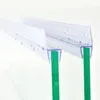 A close-up shot of a clear plastic shower door seal attached to two pieces of green glass. Podgląd zdjęcia produktu